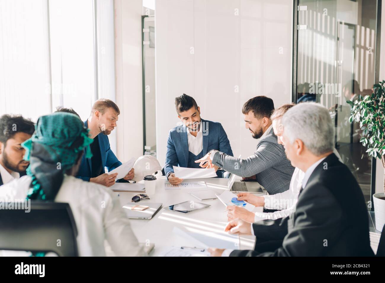 Young intelligent caucasian businessmen sharing his project ideas with executive business team creating plan, analyzing market and studying graphs cha Stock Photo