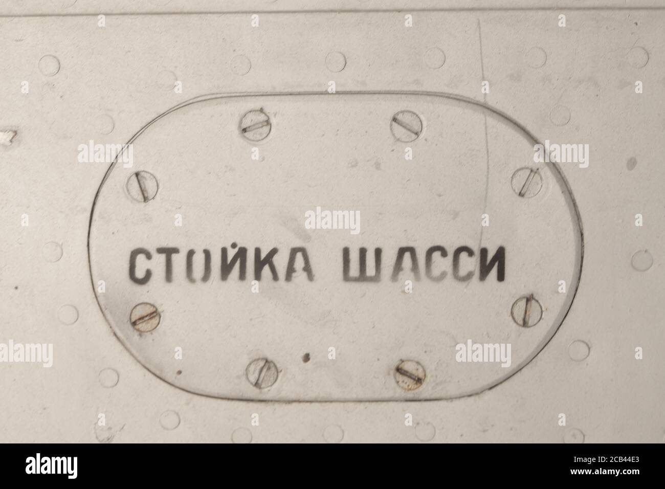 Old silver metal surface of the aircraft fuselage with rivets. The inscription in Russian 'landing gear' Stock Photo