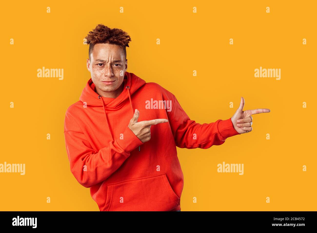 Young adult man looking at camera, pointing aside Stock Photo