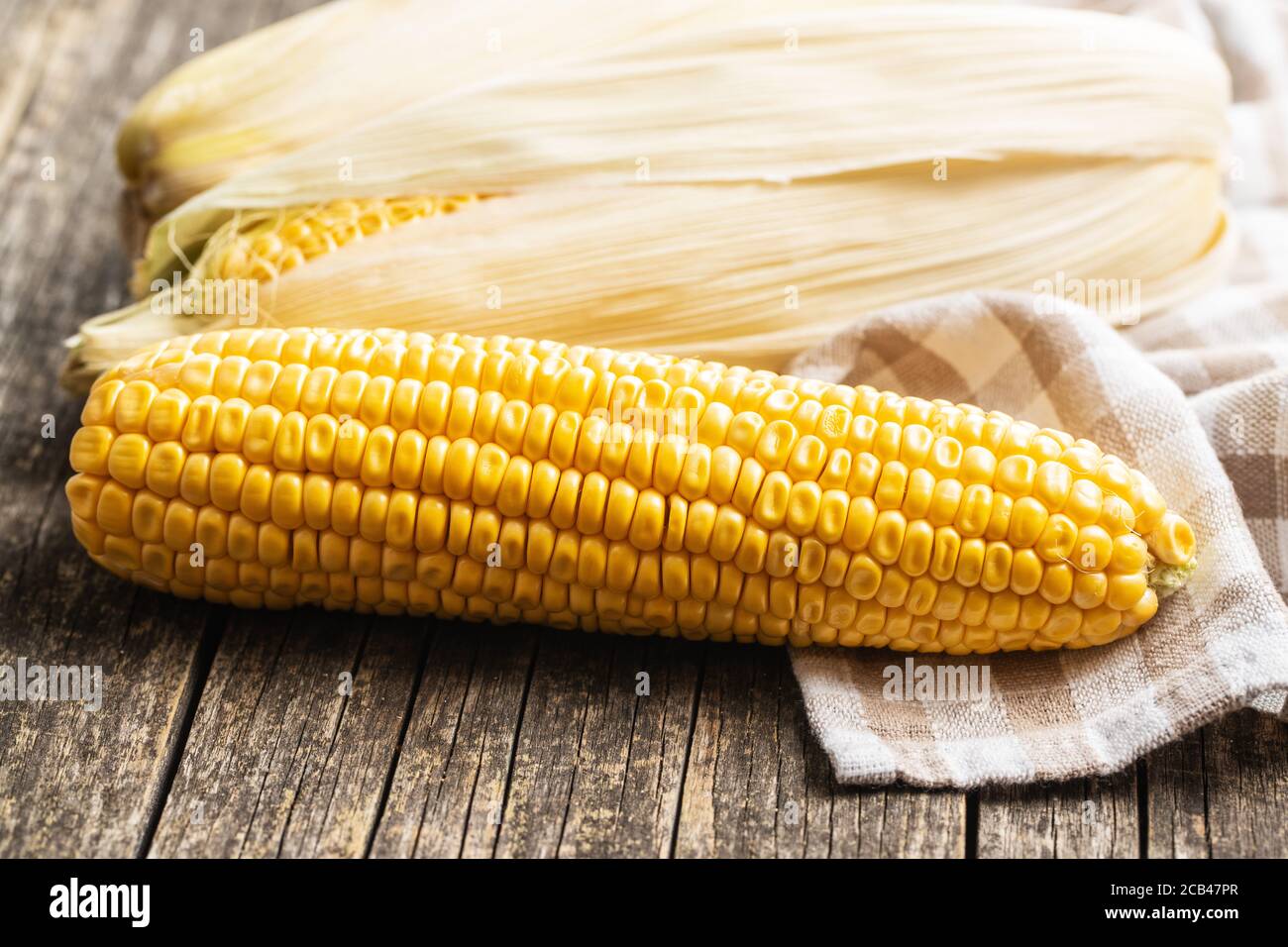 Uncooked corn cob on wooden table. Stock Photo