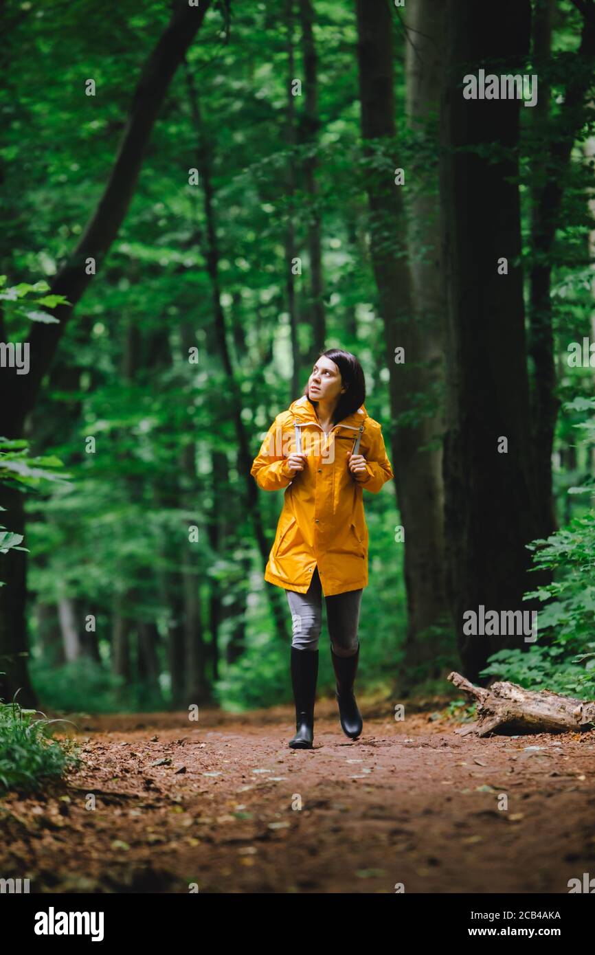 woman in yellow raincoat walking by rainy forest Stock Photo - Alamy
