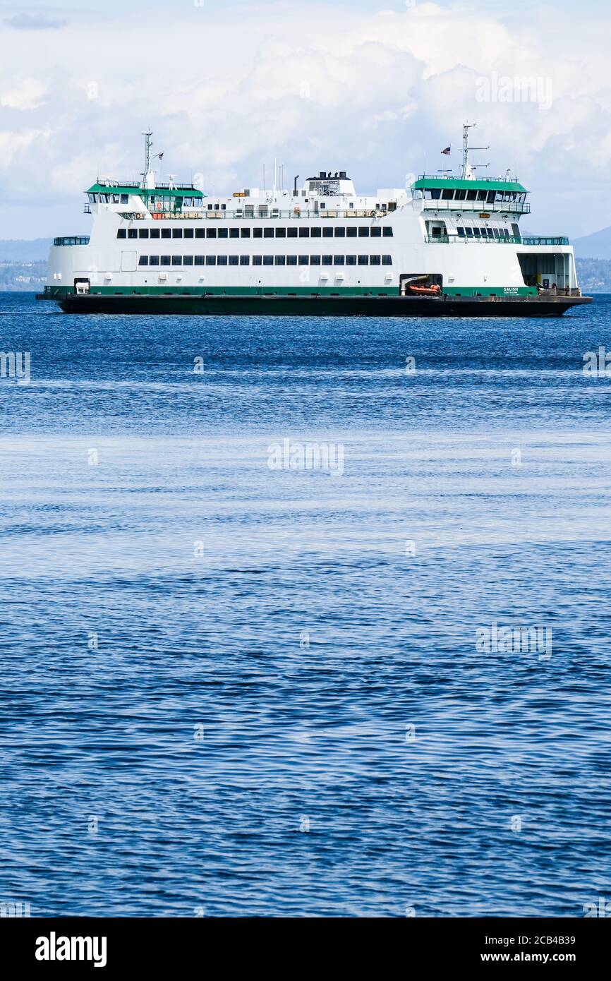 Washington State ferry moving across Puget Sound in a partially cloudy day Stock Photo
