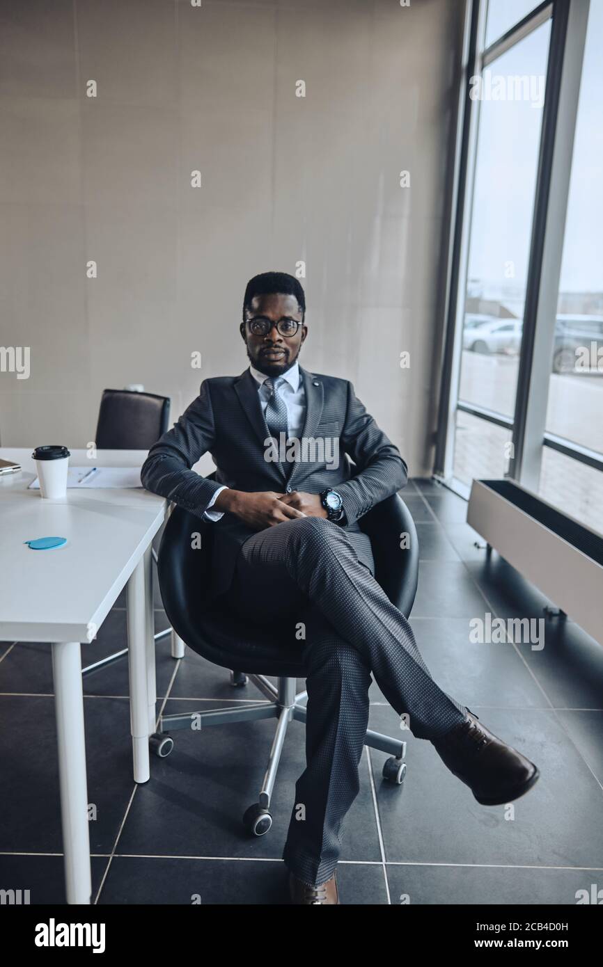 handsome stylish black businessman in glasses sitting in office. full  length photo. free time. lifestyle Stock Photo - Alamy, image size:866x1390