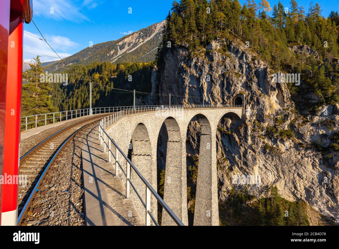 Travel with the red Rhaetian railway sightseeing train Bernina Express running over Landwasser Viaduct on sunny autumn day with blue sky cloud, Canon Stock Photo