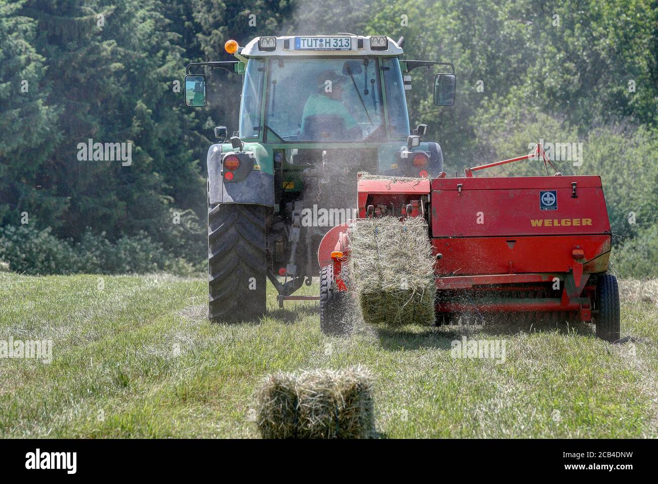 Trossingen, Germany, June 25th, 2020. Modern Fendt 313 tractor in the field, pressing hay into bales with a forty year old Welger baler. Stock Photo