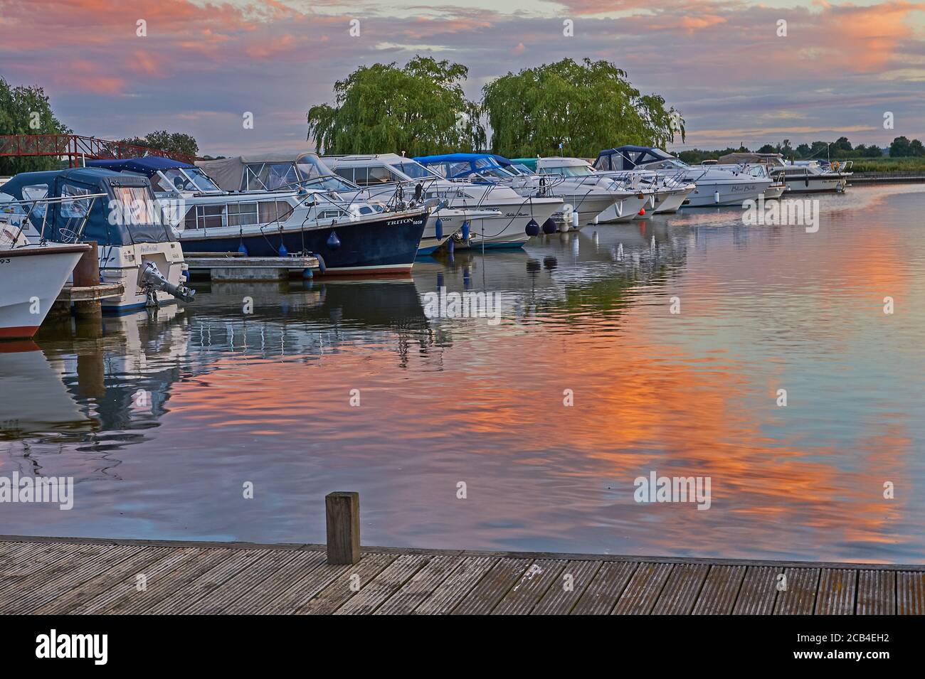 Potter Heigham, Norfolk Broads and boats moored in the marina with a colourful sky reflected in the water. Stock Photo