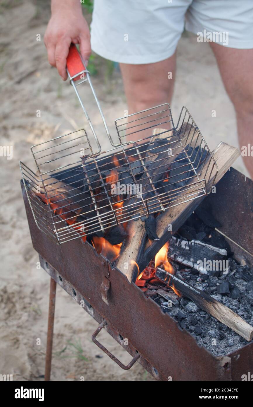 Burning firewood with flame through bbq grill grates on beach, summer picnic concept Stock Photo