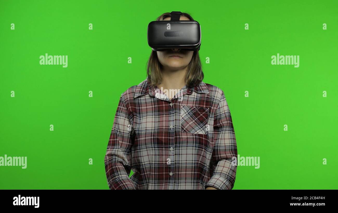 øjenbryn inerti Hare Young woman put on VR headset helmet to play game. Watching virtual reality  3d 360 video. Female isolated on chroma key green background in studio.  Future technology. Girl in VR goggles say