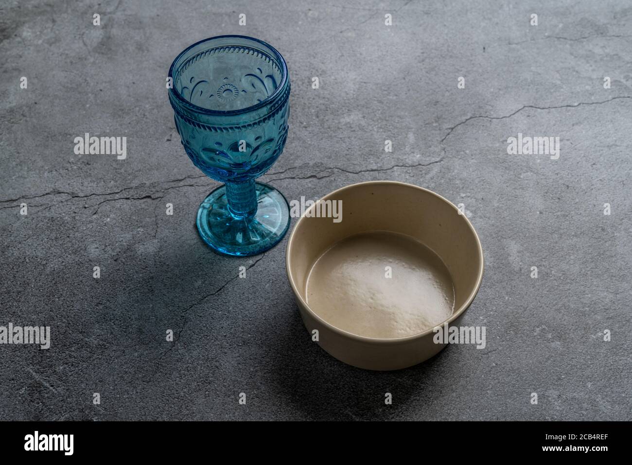 Tableware and decorations for serving a festive table. Plates, wine glasses and cutlery with gray decorative textile on white background. Stock Photo