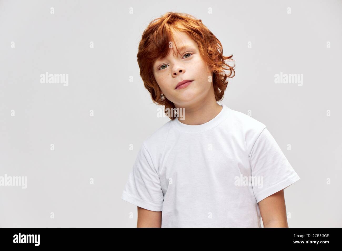 Red haired child in a white tshirt tilted his head to one side red