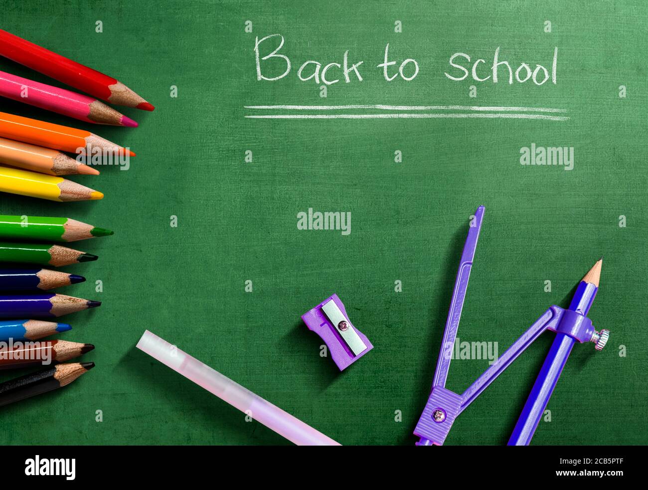 Colored pencils and stationery with the text of back to school on green ...