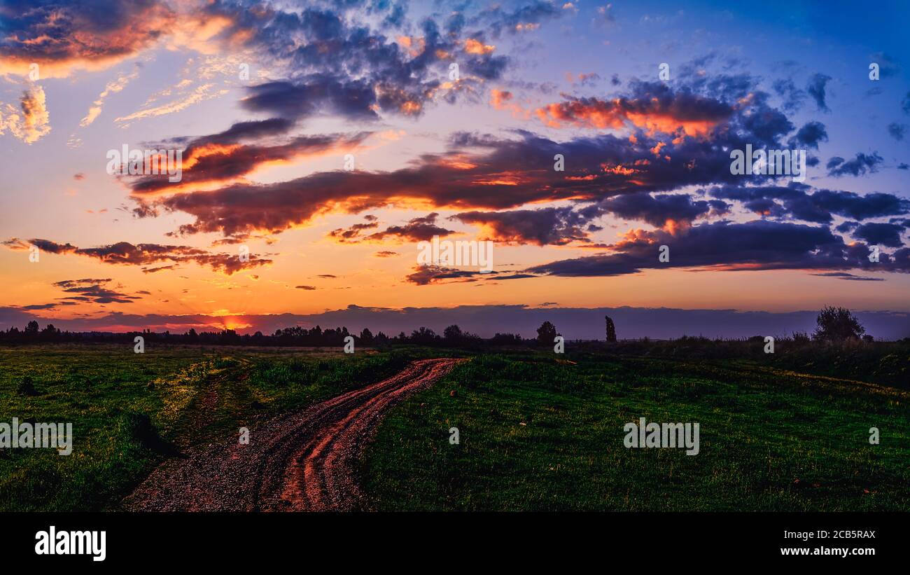 Bright sunlight shining through the clouds against the backdrop of a breathtaking evening sky at sunset. panorama, natural composition Stock Photo