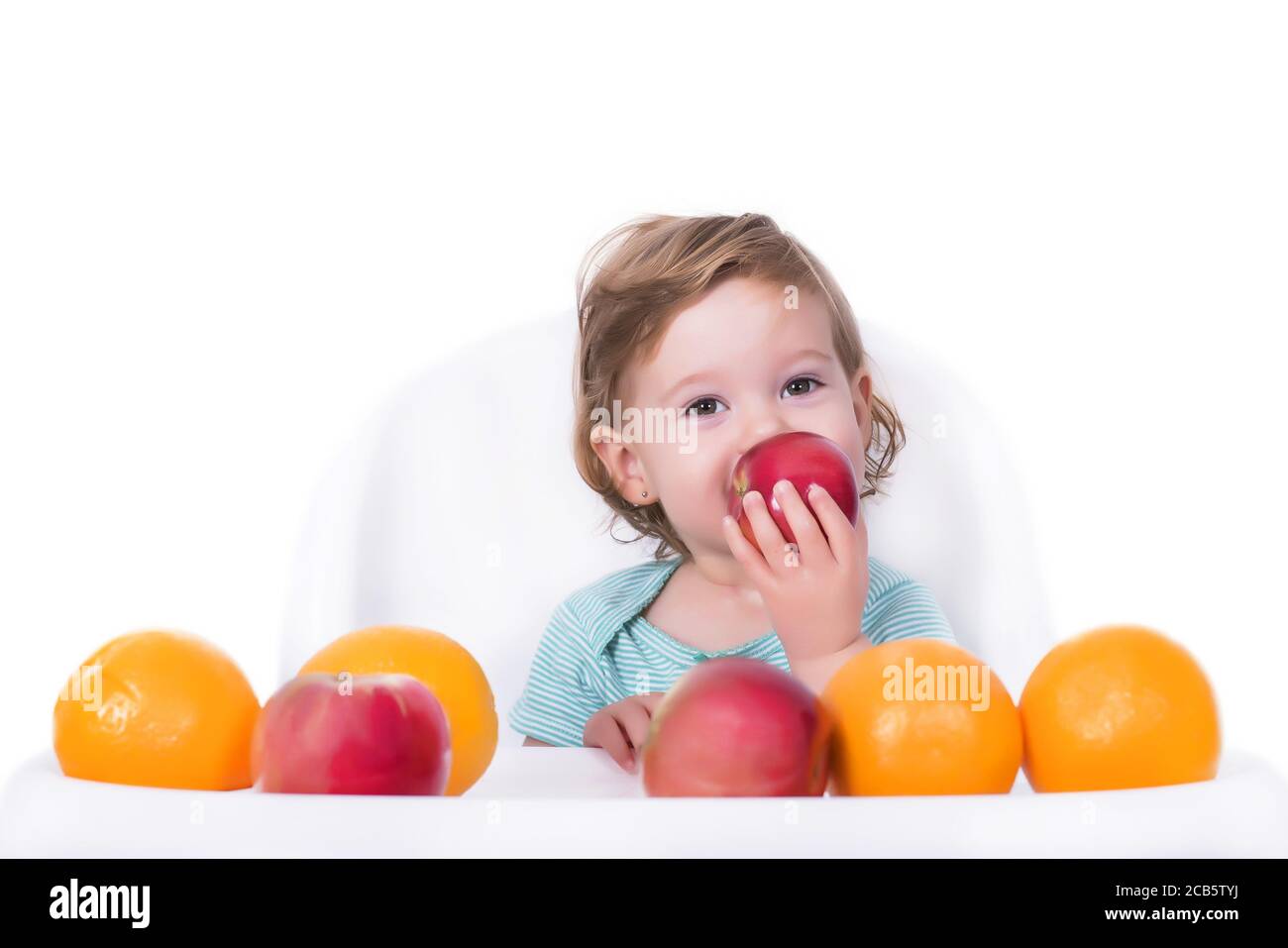 An adorable baby playing with apples and oranges on an isolated background Stock Photo