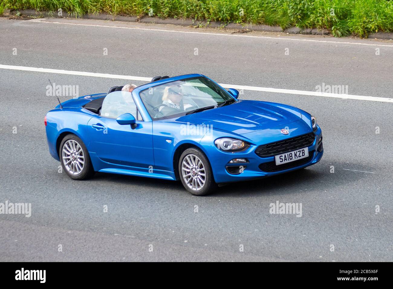2018 blue Fiat 124 Spider Classica Multi; Vehicular traffic moving vehicles, cars driving vehicle on UK roads, motors, motoring on the M6 motorway highway network. Stock Photo