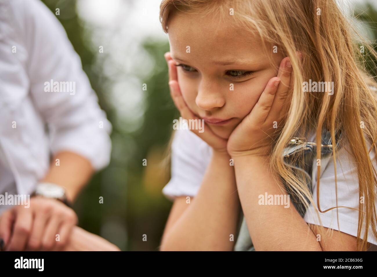 Sad girl is holding hands under chin Stock Photo