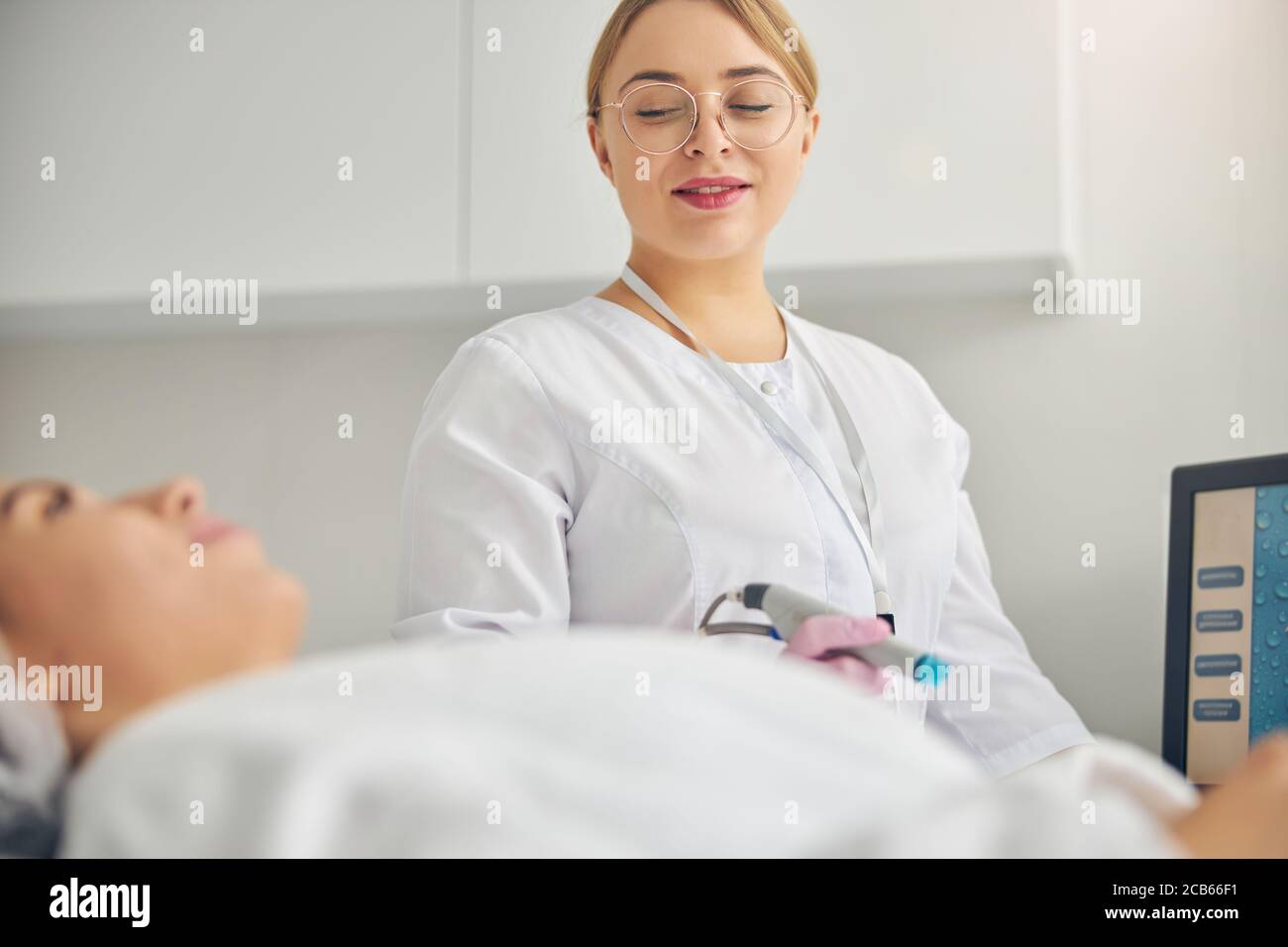 Doctor with a hydradermabrasion device looking at her patient Stock Photo