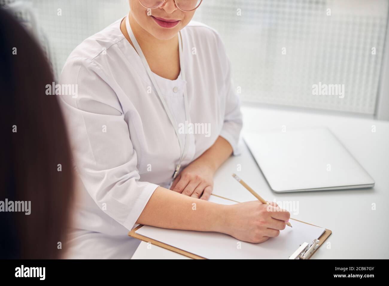Doctor with a pencil listening to her patient Stock Photo