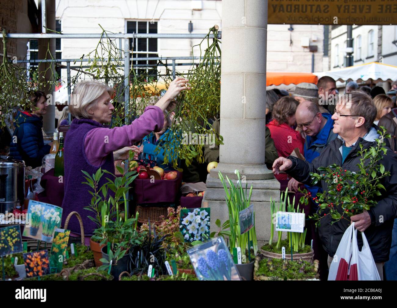 A stall holder hands a bunch of mistletoe to a Christmas shopper at a farmers market Stock Photo