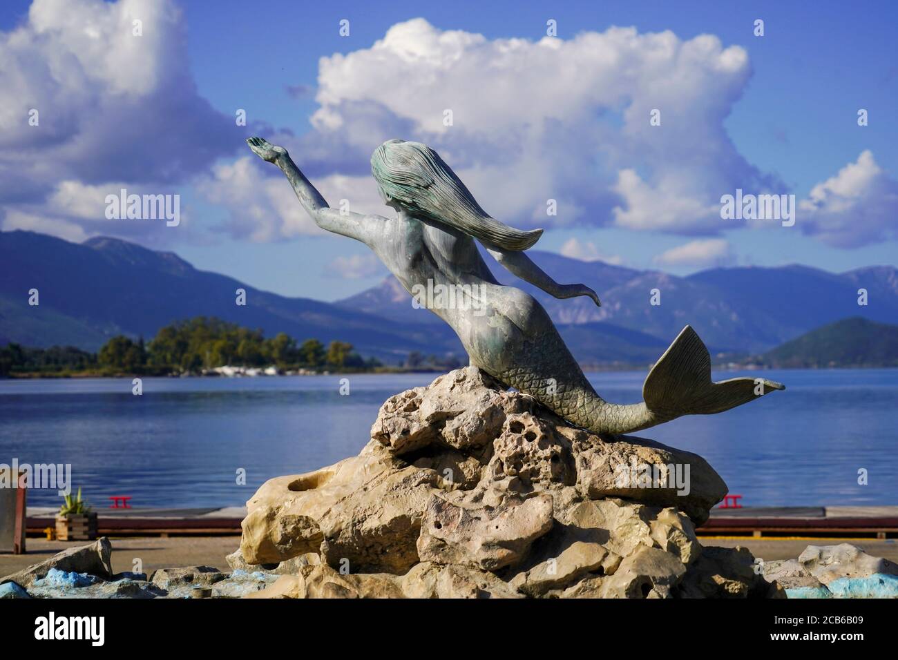 Mermaid statue and water fountain on the waterfront of Poros Town, Greece. Poros is a small Greek island-pair in the southern part of the Saronic Gulf Stock Photo