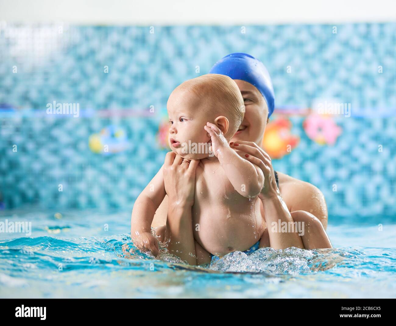 Swimming class for infants. Young mother supporting her baby in