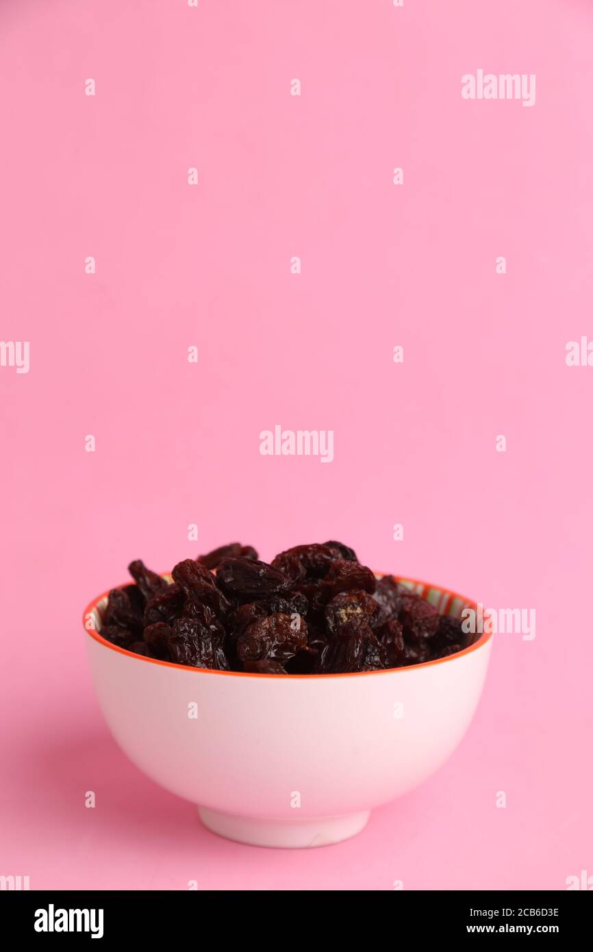 Close up shot of organic seedless sweet raisins in a bowl on a pink ...