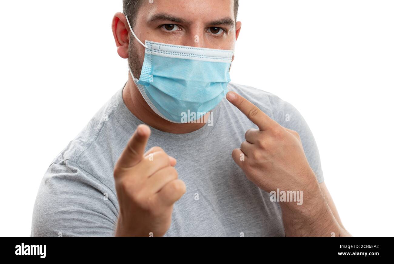 Adult man pointing index finger at disposable surgical or medical mask and screen as sars coronavirus covid pandemic prevention isolated on white stud Stock Photo