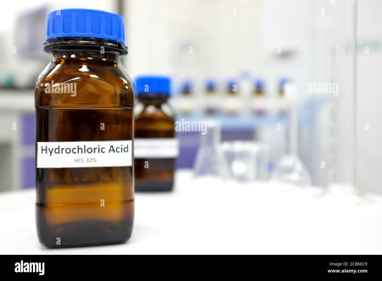 Selective focus of strong Hydrochloric acid solution in brown amber bottle. Blur laboratory backdrop with copy space. Stock Photo