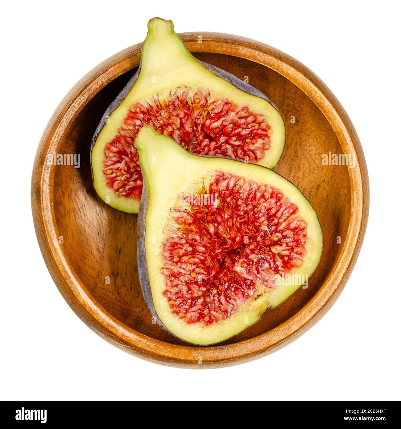 Fresh fig cut in two halves, in a wooden bowl. Fruit with purple skin and red flesh. Common figs can be eaten fresh, dried or as jam. Ficus carica. Stock Photo