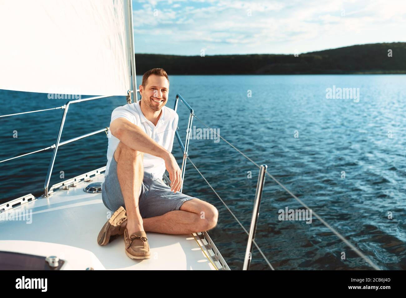 Joyful Man Sitting On Yacht Boat Deck Sailing Across Sea Stock Photo