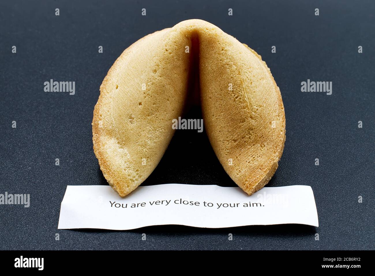 Chinese fortune cookie with message isolated on dark background Stock