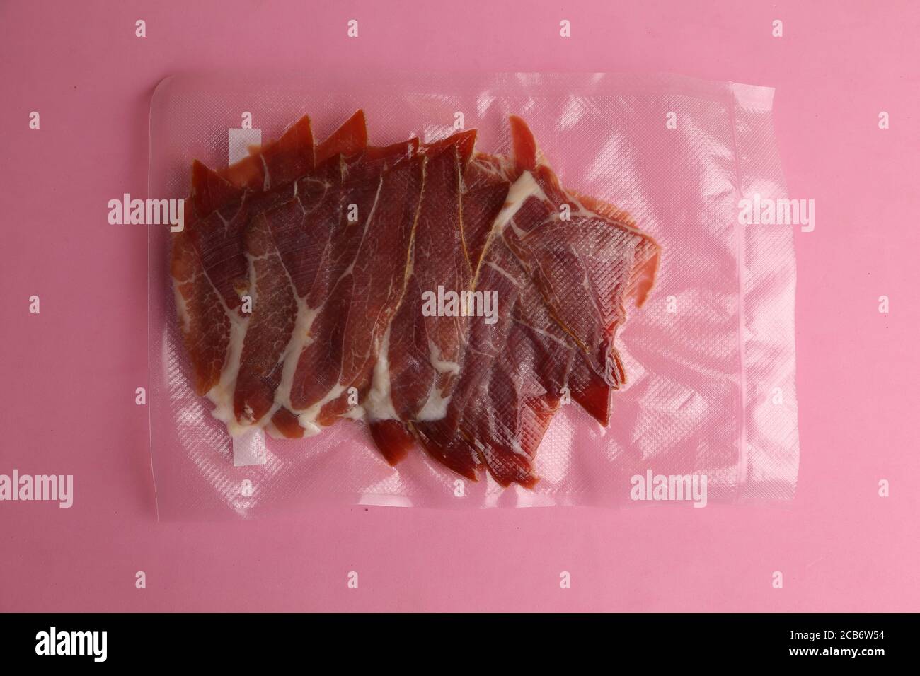 Overhead shot of a vacuumpacked serrano ham isolated on a pink