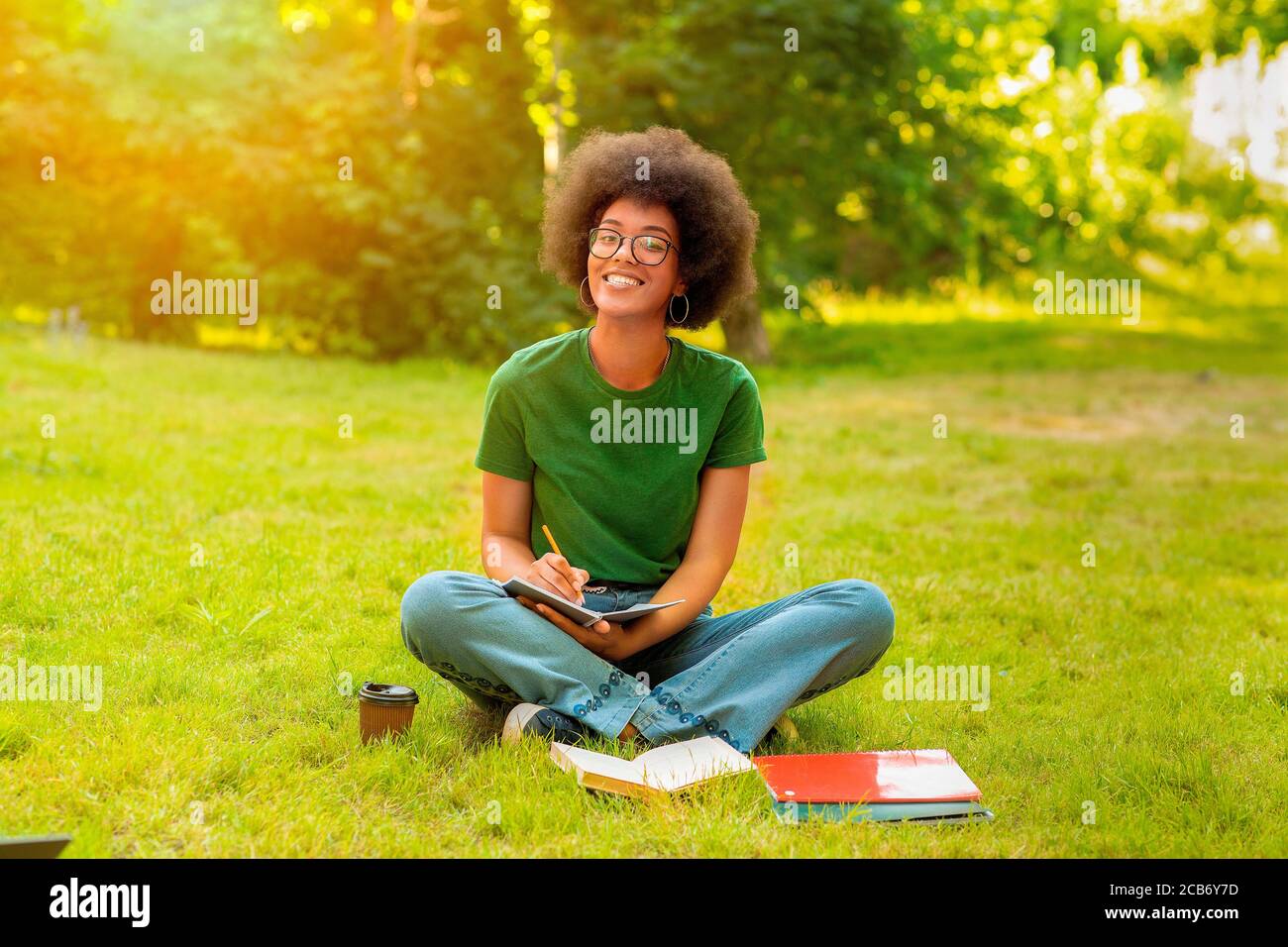 Portrait Of Black Cheerful College Student Girl Posing While Studying Outdoors Stock Photo