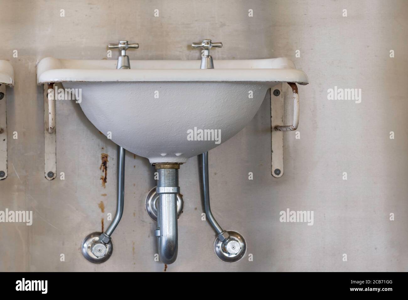 Old but restored iron baked enamel wash basins or sinks mounted on a wall at Cockatoo Island dockyard in Sydney Harbour, Australia Stock Photo