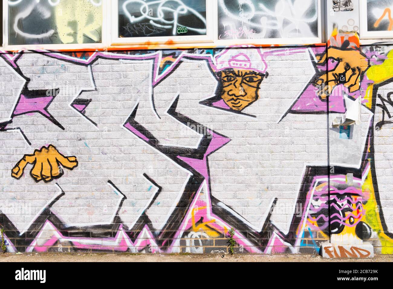 England London Stratford Park Hackney Wick graffiti brick wall letters face head hat hands windows ring Stock Photo