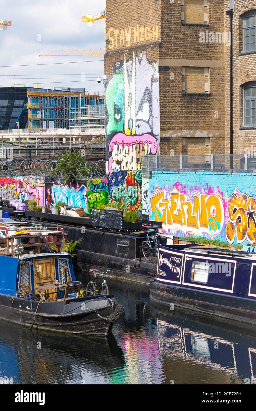 England London Stratford Park Hackney Wick graffiti letters pictures figures wall towpath barges houseboats bicycle solar panels large white dog Stock Photo