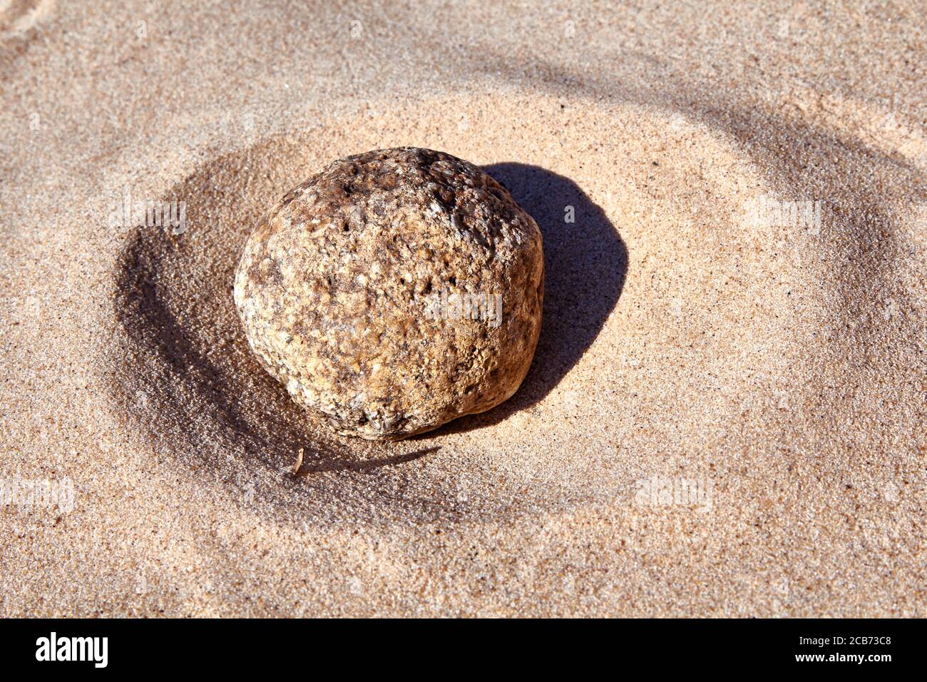 round rock in the sand on the sunny day at the Baltic sea shore Stock Photo