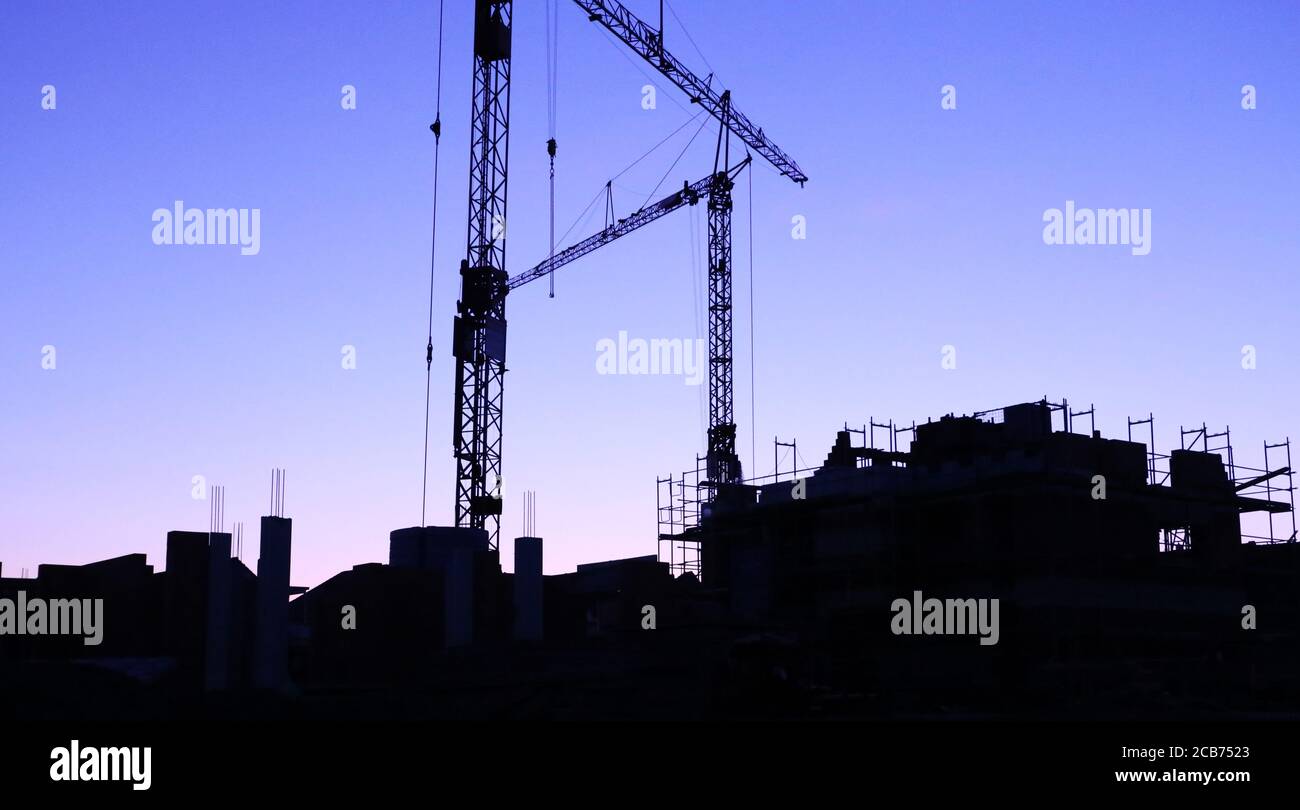 Construction site with cranes at nightfall Stock Photo