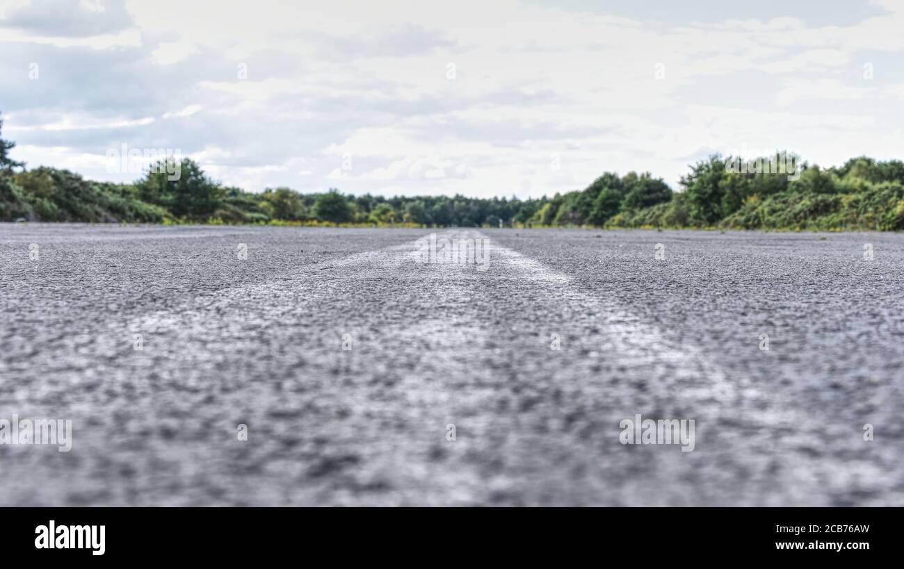 A faded white line on a disused runway at Blackbushe, Yateley Common in Hampshire Stock Photo