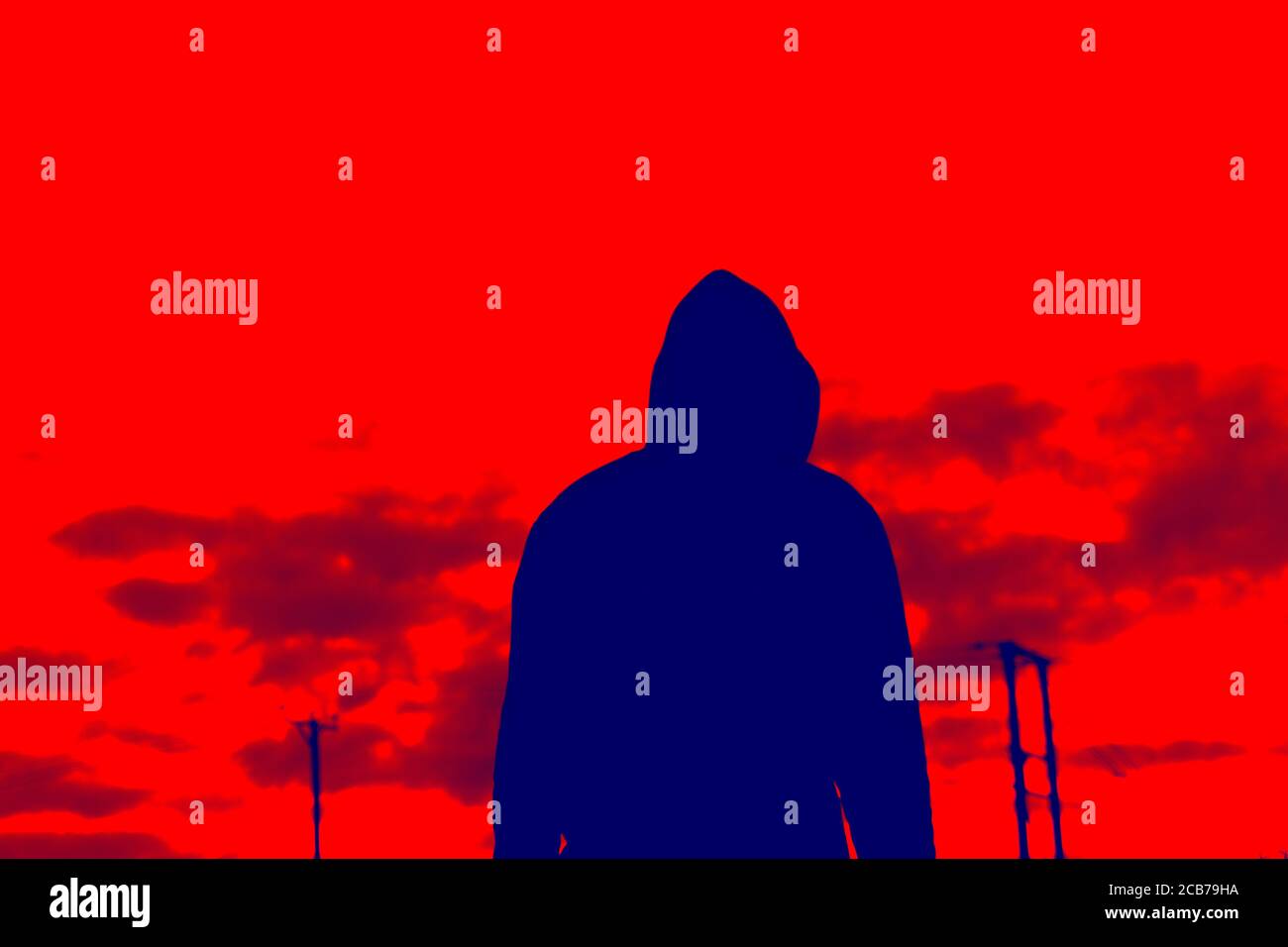 A blue, red duo tone edit. A hooded figure standing back to camera, looking at the sky. Stock Photo