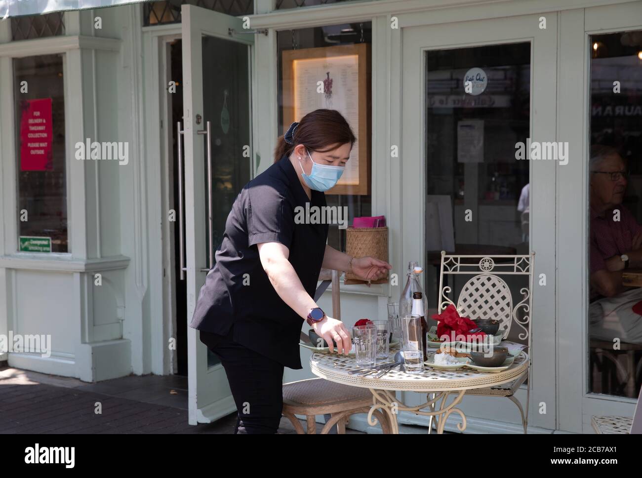 Sevenoaks, Kent, 11th August 2020, A waitress clears a table in Sevenoaks, Kent as people The forecast is for 32C sunny with light winds and is to continue with high temperatures until Thursday when thundery showers arrive. Credit: Keith Larby/Alamy Live News Stock Photo
