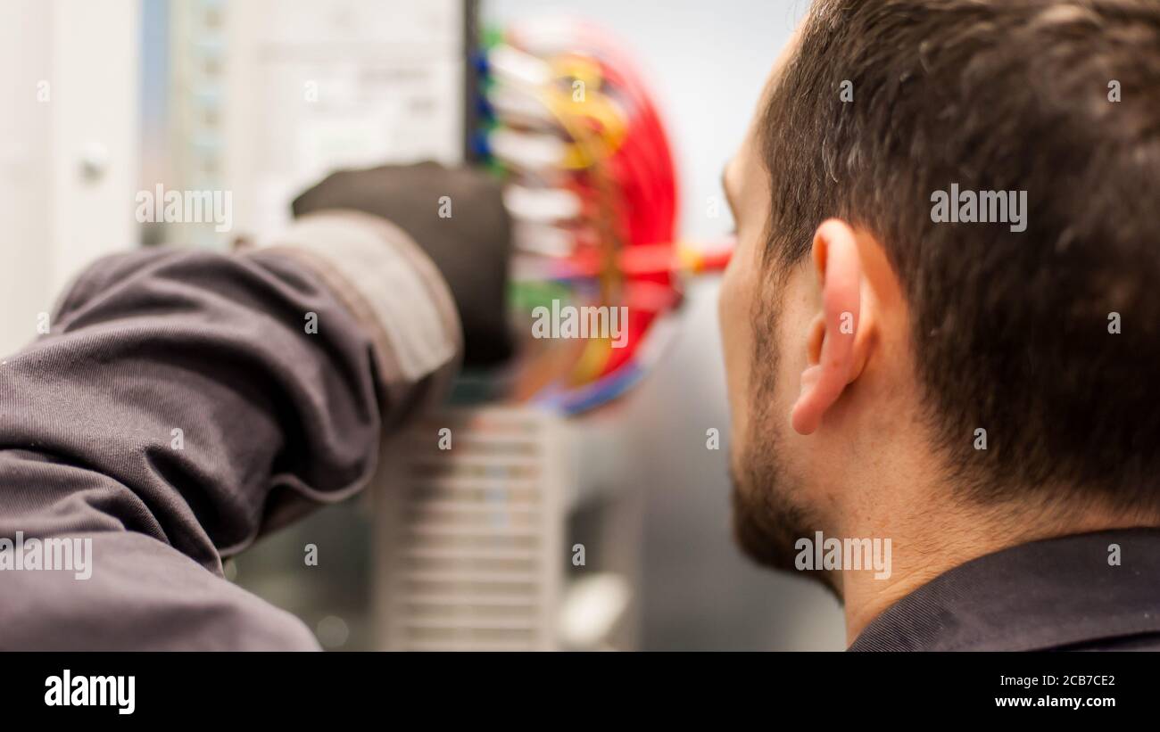 Closeup of electrician engineer works with electric cable wires of fuse switch box. Electrical equipment Stock Photo