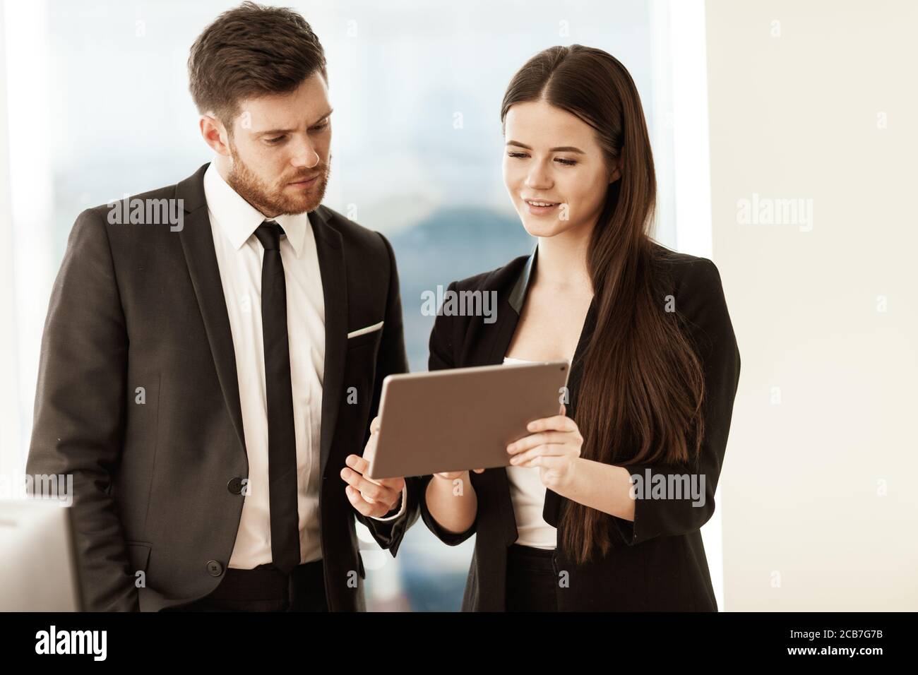 Successful business and modern technology concept. Young businesswoman and happy smiling businessman working together using tablet computer. Two Stock Photo