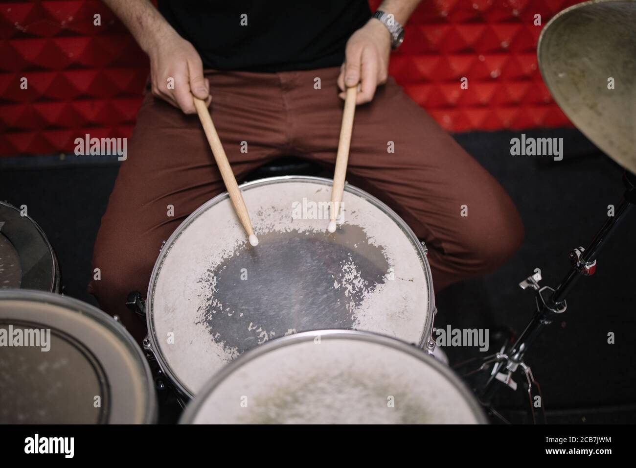 Cropped view of man playing drums in studio. Close-up view of male hands with sticks playing the drums in music studio. Stock Photo