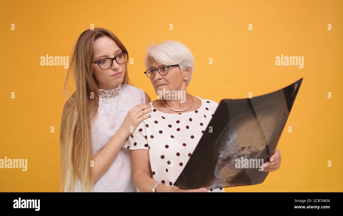 Young woman confronting worried senior lady holding a x-ray o MRI head scan. High quality photo Stock Photo