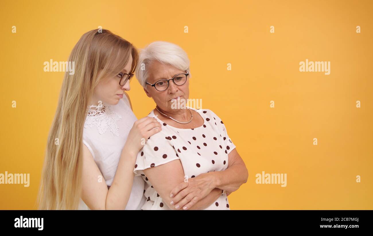Young woman calming down senior lady after bad news. Family love and care concept. High quality photo Stock Photo