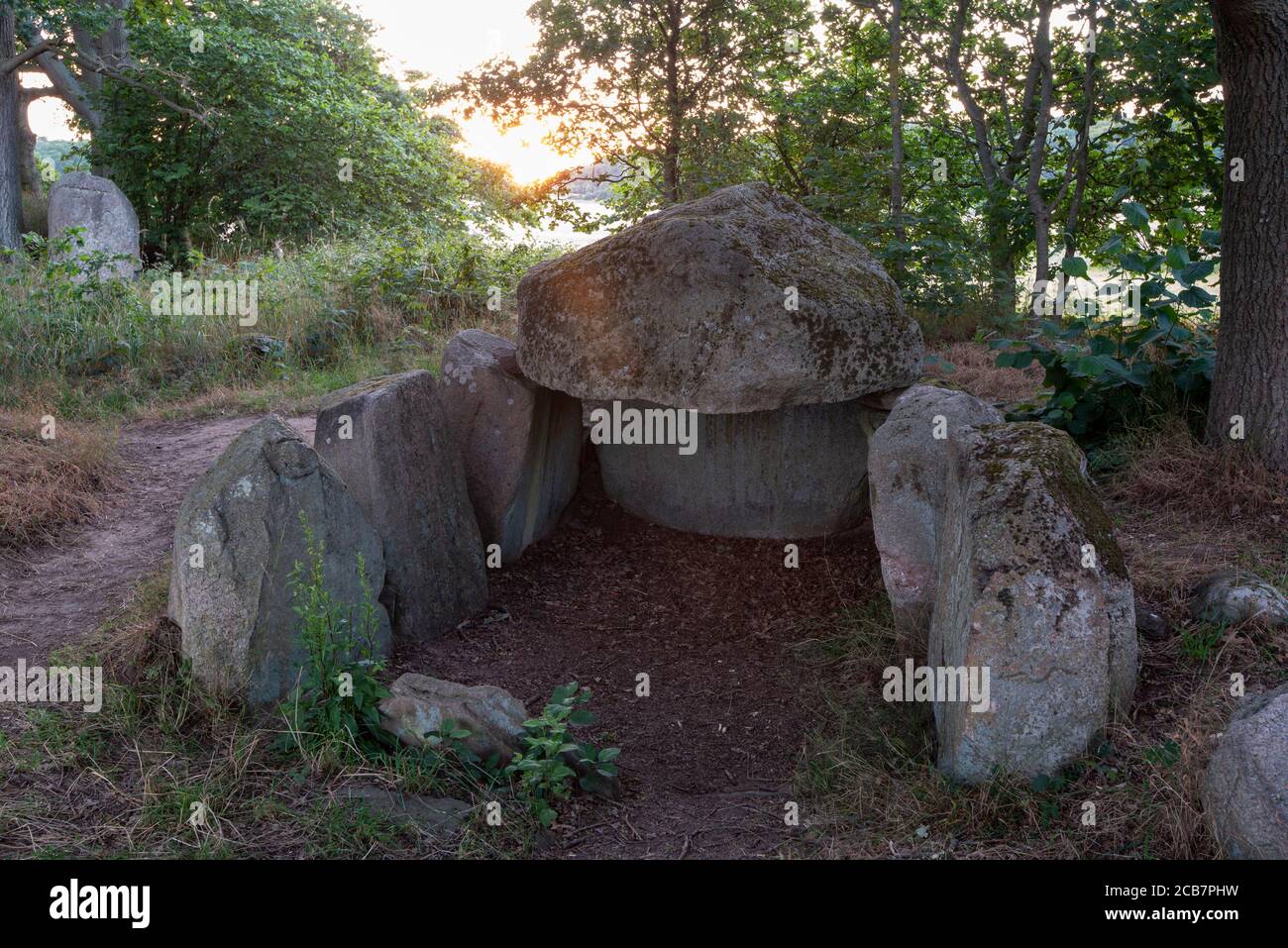 Lancken Granitz, Germany. 07th Aug, 2020. The sun sets behind a megalithic tomb. The megalithic tombs near Lancken-Granitz on the island of Rügen are eight tombs of the Neolithic Funnel Beaker Culture. Credit: Stephan Schulz/dpa-Zentralbild/ZB/dpa/Alamy Live News Stock Photo