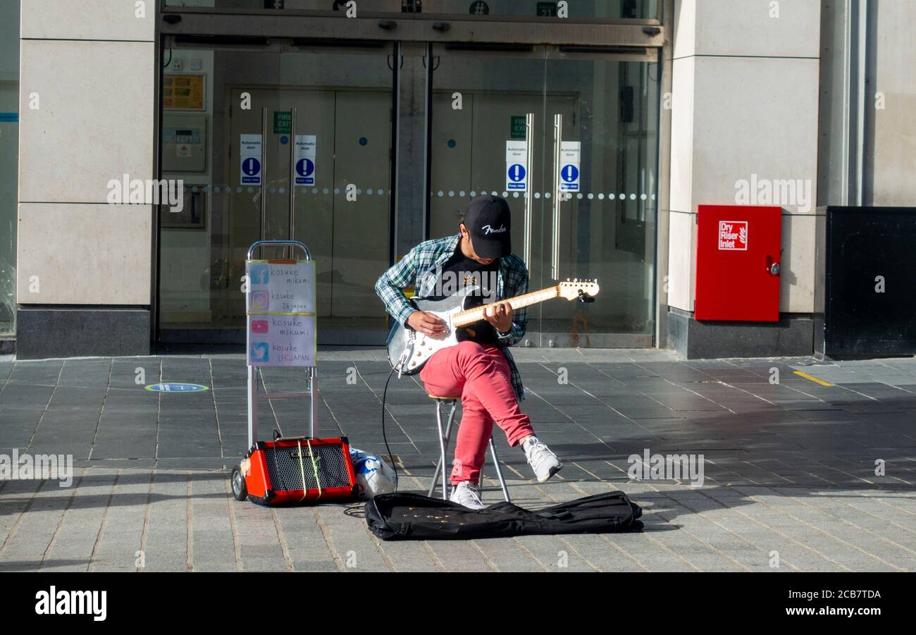 A busker playing the electric guitar to an empty High Street in