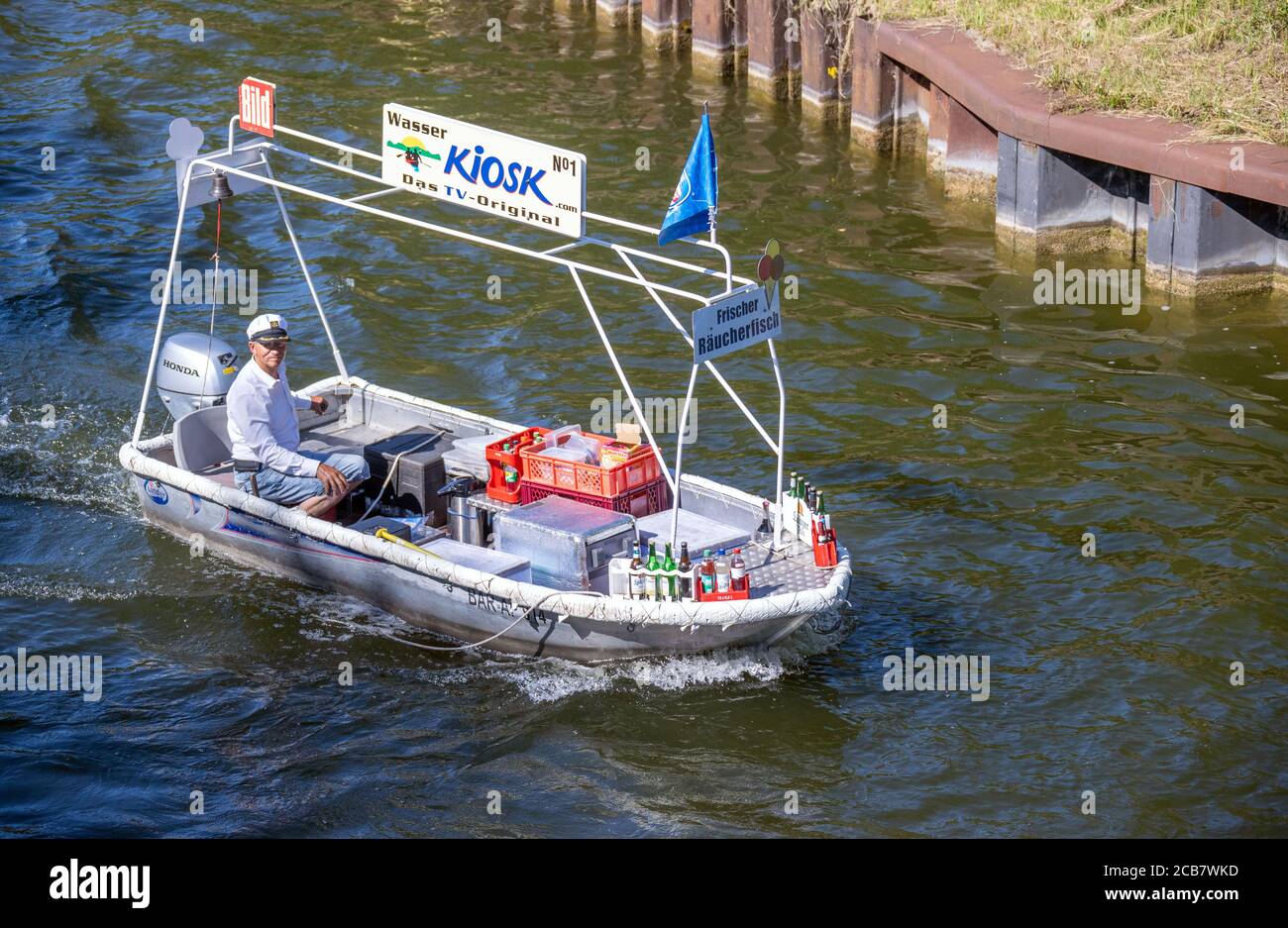 Canow, Germany. 06th Aug, 2020. Jens Winkelmann is on the move with his water kiosk on the Müritz-Havel Canal and supplies holidaymakers on houseboats, yachts and canoes with ice, cold drinks or freshly smoked fish. Every day during the season he is on the waterways and lake at the state border of Brandenburg and Mecklenburg for up to 80 kilometres. The Brandenburg native has converted his four-metre-long, old barge into a kind of "floating consumption" with a freezer and and fresh-keeping boxes. Credit: Jens Büttner/dpa-Zentralbild/ZB/dpa/Alamy Live News Stock Photo