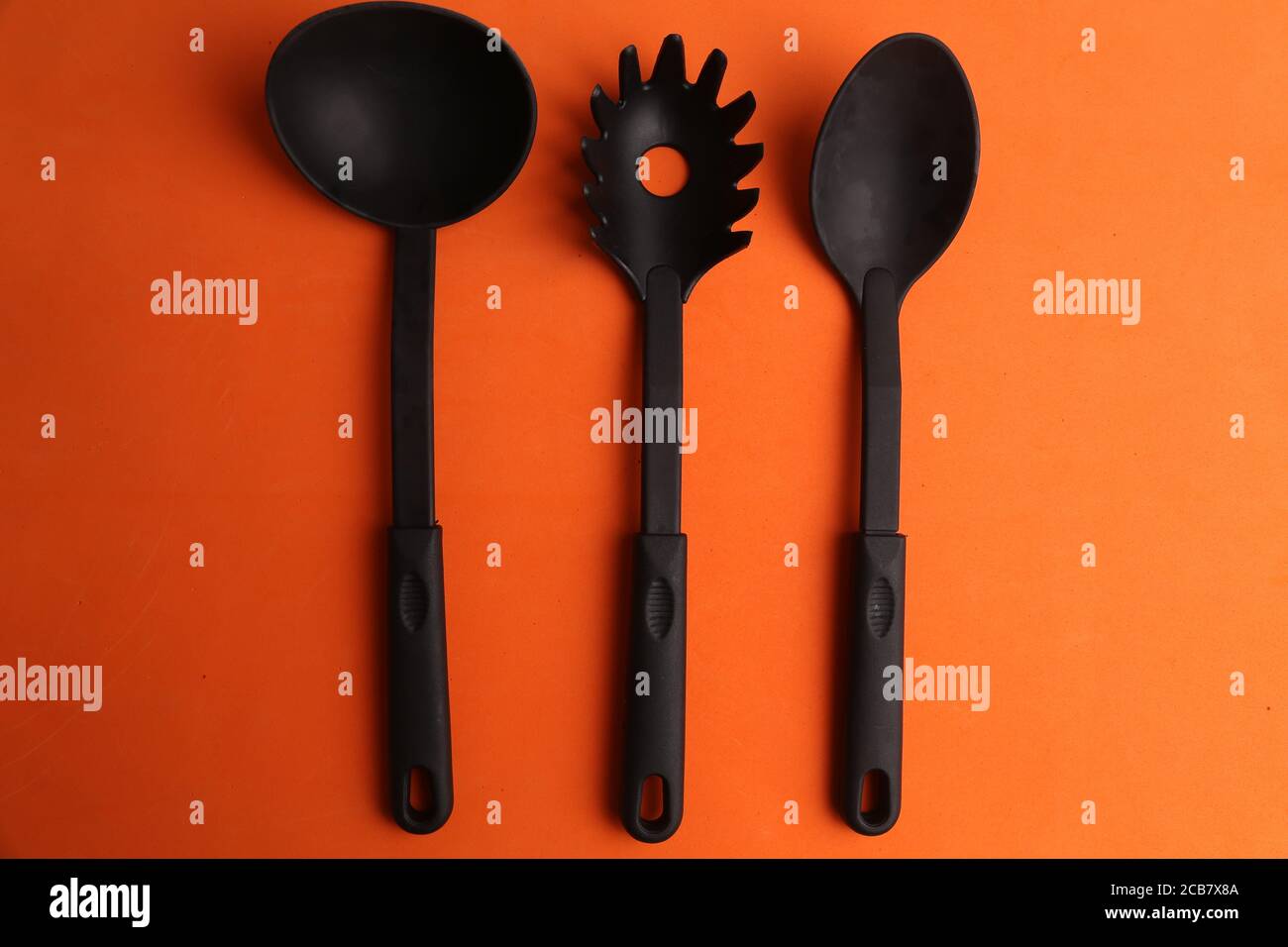 Plastic cooking utensils on an orange background Stock Photo