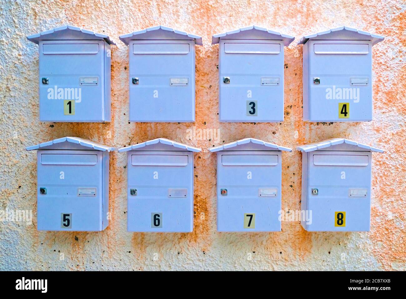 Eight letter boxes on a wall, waiting for a snail mail love letter. Stock Photo